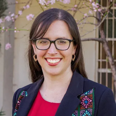 Christine Barker, FIRM's Executive Director, outdoors in front of a blossoming tree.