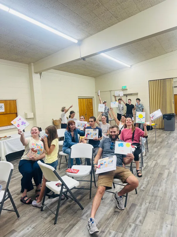 An English class at FIRM, students seated in a circle of chairs with their workbooks and the teacher standing among them.