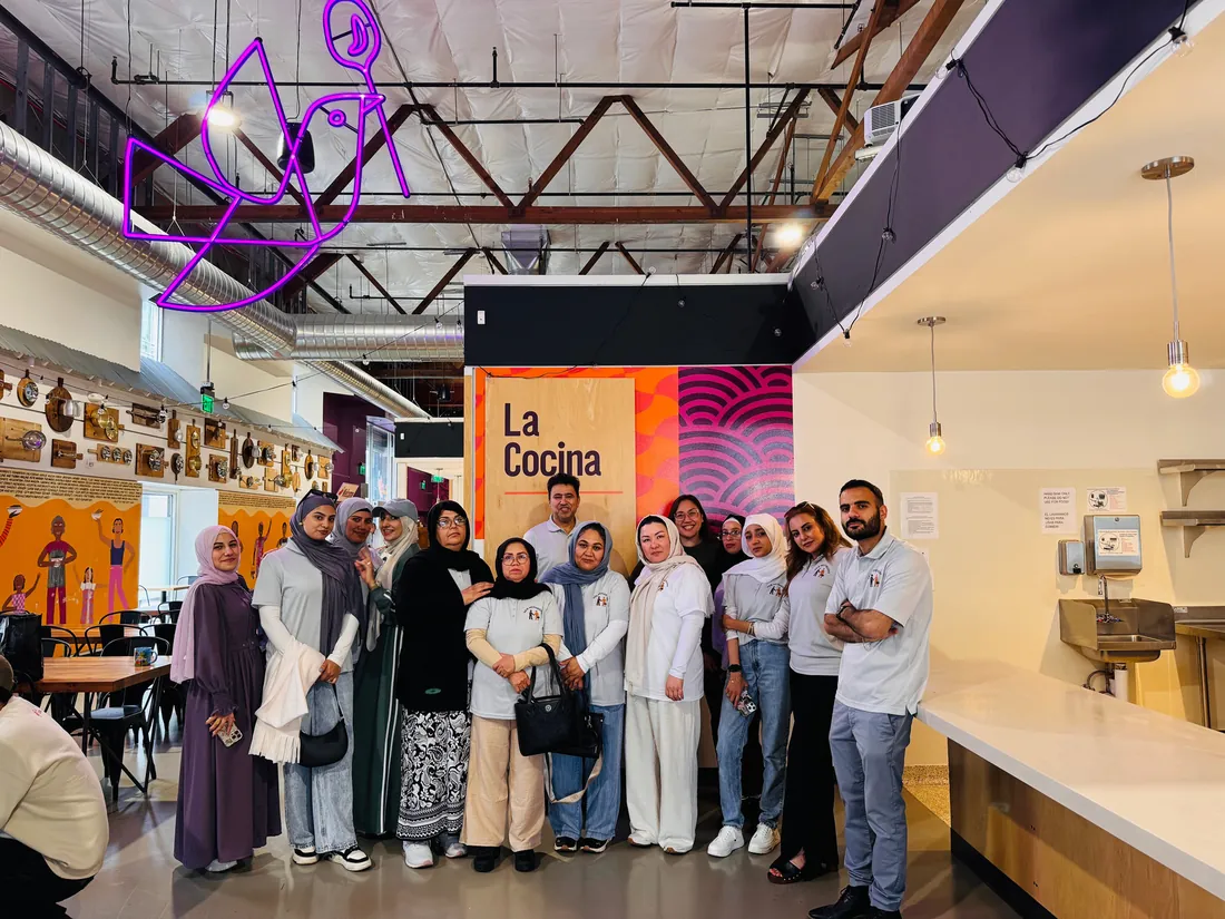 The FIRM entrepreneurship group touring a shared commercial kitchen, standing together between the counters.